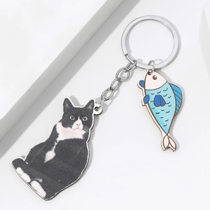 Detail shot of 3D effect acrylic keychain featuring a tuxedo cat and blue fish charms