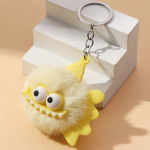 Detailed close-up of fluffy yellow monster keychain with large eyes and silver metal ring