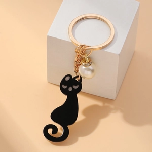 Elegant black cat keychain with gold ring and white faux pearl accent on stone base