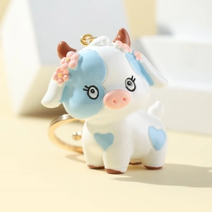 Cute 3D cartoon cow keychain with heart pattern and blue spots on a geometric stand