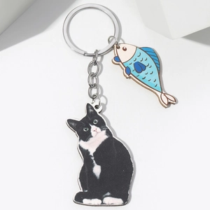 Close-up of cute 3D cartoon cat and blue fish charms on a silver metal keychain