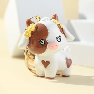 Cute 3D cartoon cow keychain with heart spots and yellow flowers on white geometric background
