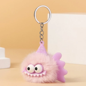 Close-up of pink plush monster keychain with big eyes, purple fins and silver chain