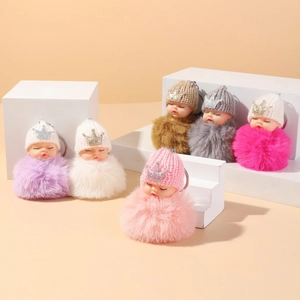Detailed view of plush sleeping baby keychains with glitter crowns in various colors