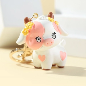 3D cute cartoon cow keychain made of resin with golden ring and pink heart details