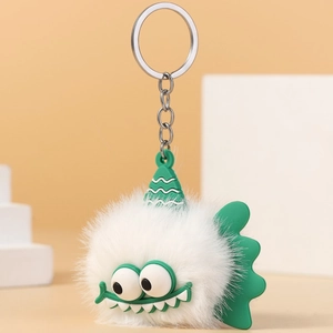 Detail of white furry monster keychain with green silicone hat and metallic ring