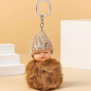 Detailed view of handmade sleeping doll keychain with brown faux fur and crown hat