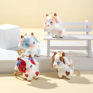 Detailed view of four colorful 3D cartoon cow keychains on a miniature white bench