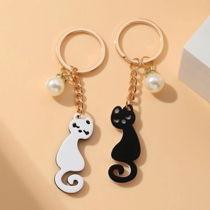 Detailed close-up of cute black and white acrylic cat keychains with pearl charms