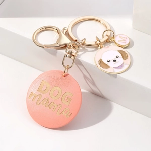 Close-up of pink DOG MAMA wooden keychain with white poodle charm and gold hardware