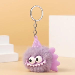 Detail of a purple plush monster keychain with big eyes and a tiny wave-patterned hat