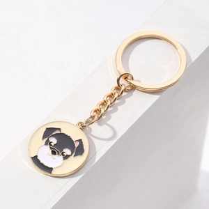 Detailed close-up of a gold metal keychain featuring a cute black and white schnauzer pendant