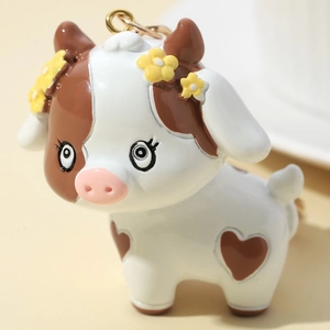 3D cartoon cow keychain with heart-shaped spots and yellow flower decor on a gold ring