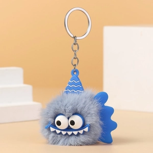 Detailed close-up of gray plush monster keychain with blue silicone fins and silver ring