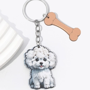 Close-up of a white puppy keychain with a brown bone charm on a white stone prop