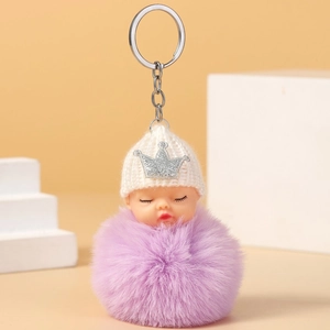 Detailed close-up of a plush baby doll keychain with a white knit hat and purple faux fur ball
