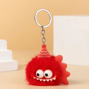 Close-up of fluffy red monster keychain with big eyes and silver metal ring on white block