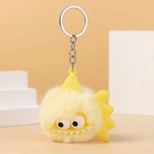 Close-up of yellow fuzzy monster plush keychain with cartoon eyes and silver metal ring