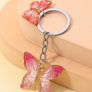 Close-up of dual pink gradient resin butterfly charms with gold trim and silver keychain