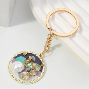 Elegante portachiavi in metallo dorato con smalto colorato, perla bianca e strass lucidi