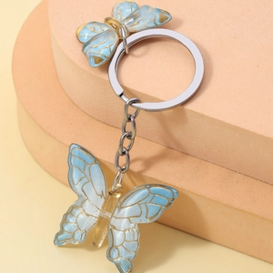 Macro shot of blue gradient butterfly keychain with gold edges and silver ring