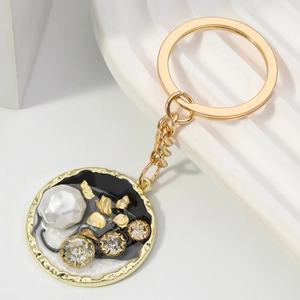 Portachiavi con ciondolo tondo dorato con perle e strass su base geometrica bianca