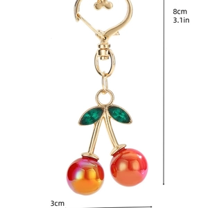 Macro detail of cherry keychain with 8cm height measurement and heart-shaped clasp