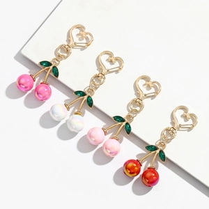 Detail of colorful cherry keychains with heart hooks and green gem leaf accents