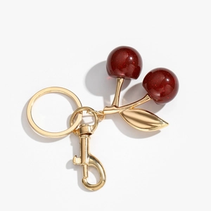 Detailed macro view of red resin cherry keychain with glitter and golden leaves charm