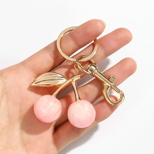 Close-up of pink glitter resin cherry keychain with gold plating and lobster clasp