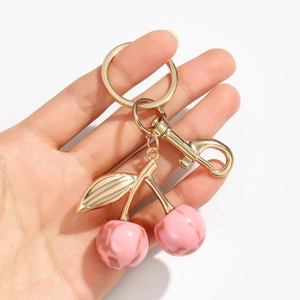 Glittery pink resin cherry keychain with gold leaf detailing on white background