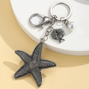 Detailed view of alloy starfish keychain with conch charm and white pearl accessory