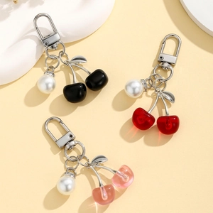 Cute mini cherry pearl keychains in red, pink, and black colors on soft background