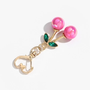 Detail of pink pearlescent cherry keychain with gold stem and green crystal leaf accents