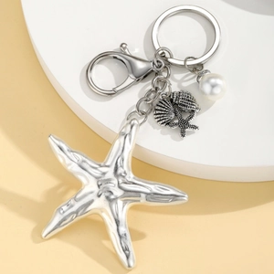 Bohemian silver starfish keychain with pearl and seashell charms on white platform