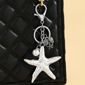Detail of silver starfish bag charm with shells and white pearl on black quilted handbag