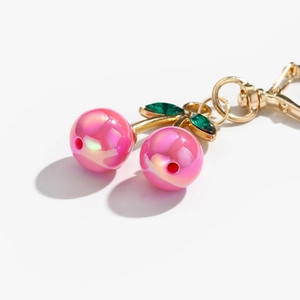 Cute pink pearlescent cherry keychain with green crystal leaves and gold metal clip