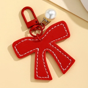 Detail of red PU leather bow keychain with white stitching and white pearl pendant charm
