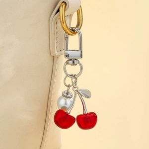 Detailed view of 3D cherry charm with pearls on a handbag leather strap