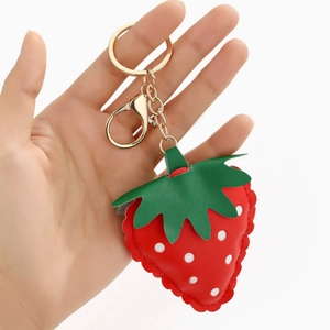 Cute red PU leather strawberry keychain with green leaves and gold hardware on white background