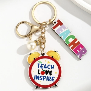 Detail of wooden book teacher keychain with Teach Love Inspire slogan and white pearl charm