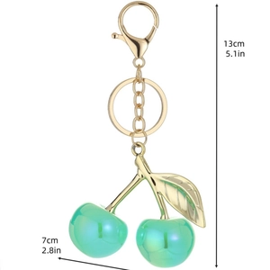Green resin cherry keychain with gold leaf details and lobster clasp on white background
