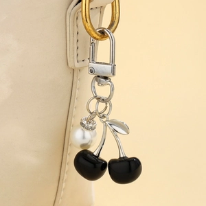 Detailed view of black resin cherry charms with white pearl on a silver keyring