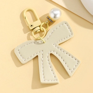 Close-up of cream leather bow pendant with white stitching and pearl detail charm