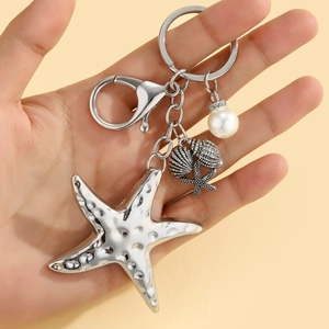 Detail of silver starfish keychain with seashell charms and white pearl accent