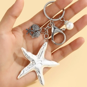 Detailed macro view of bohemian starfish keychain with shells and a white pearl charm