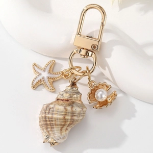 Detailed close-up of shell keychain with golden starfish and pearl scallop charms