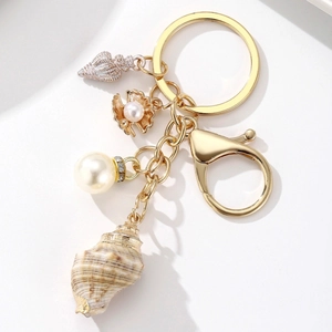 Detail shot of ocean theme keychain with natural conch, pearl and gold shell charms