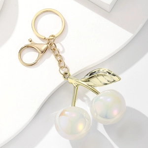Detailed macro view of pearlescent resin cherry keychain with golden leaf and alloy chain