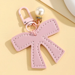 Macro detail of pink leather bow charm with pearl rhinestone and matching metal buckle
